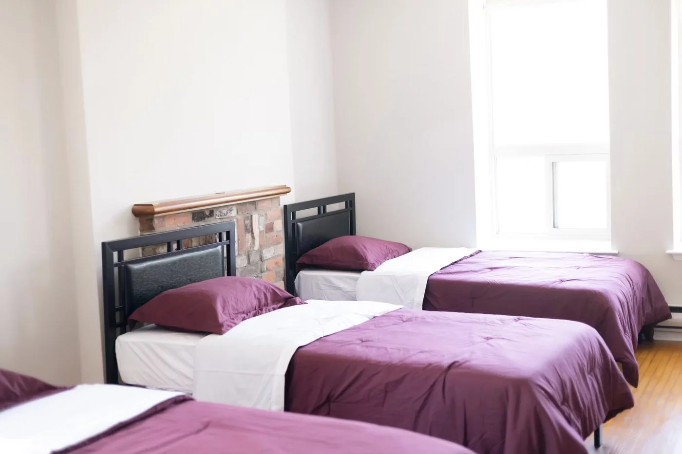 A bedroom inside L'Agapanthe with two single beds dressed in burgundy bedding.
